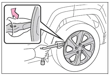 Wheel nut wrench positioned to loosen the wheel nuts before lifting